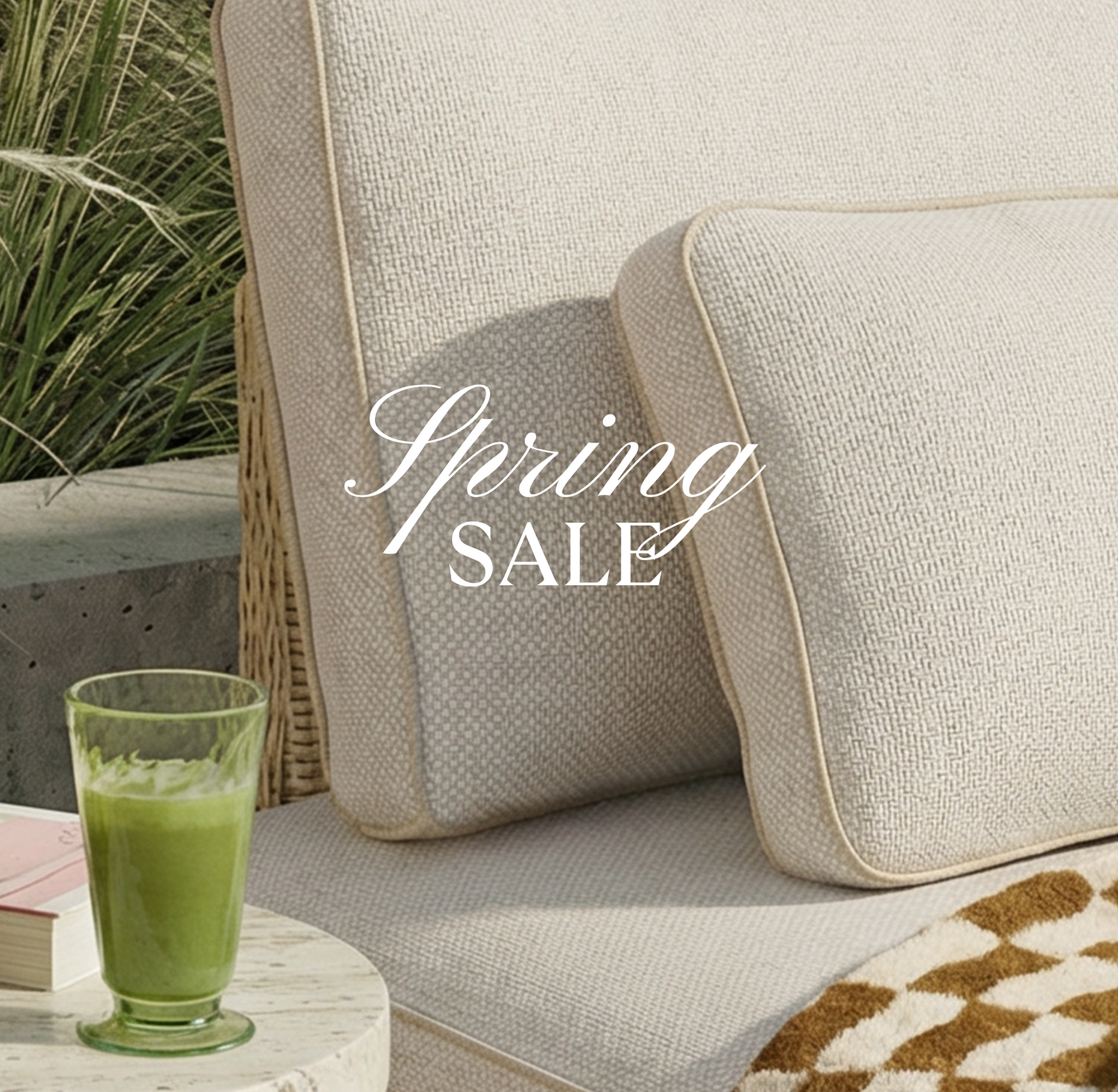 Outdoor setting with a glass of green juice on a table next to a cushioned chair, with 'Spring Sale' text overlay.