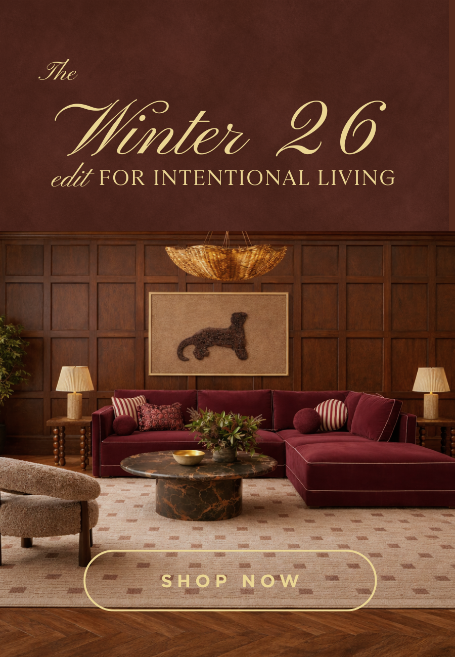 Living room with burgundy sofa, wooden walls, and decorative elements with 'The Winter 26 edit FOR INTENTIONAL LIVING' text.